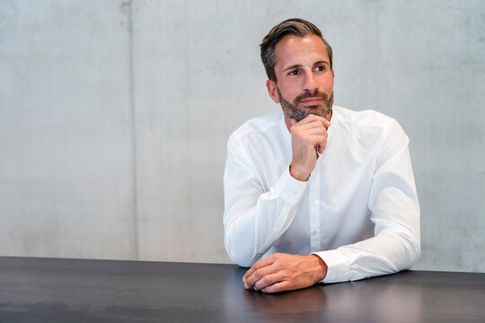 Thoughtful businessman with hand on chin in office