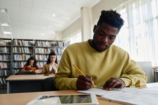 Young student writing in book at desk