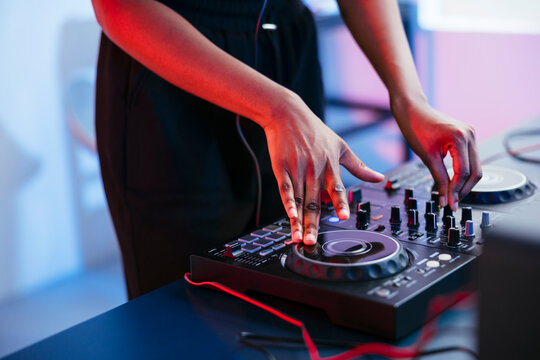 Female Dj operating sound mixer at home