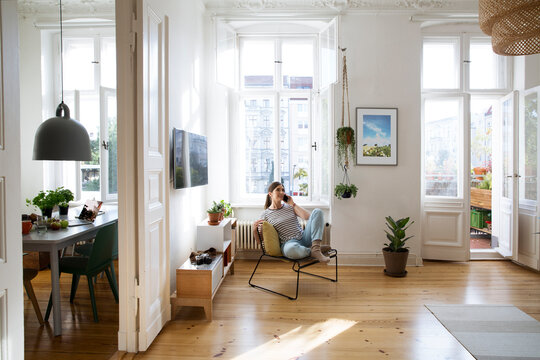 Woman at home sitting on chair talking on cell phone