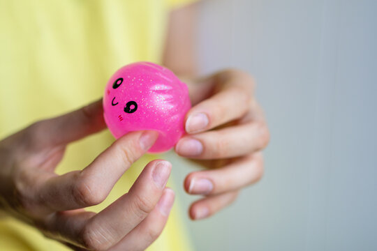 Close-up of hands holding a pink squishy toy before squeezing during sensory play. Concept of stress relief, tactile activity, relaxation and emotional balance.