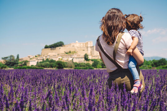 France, Grignan, back view of mother and little daughter together in lavender field looking at village