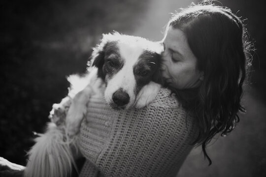 Woman hugs her border collie dog affectionately in nature