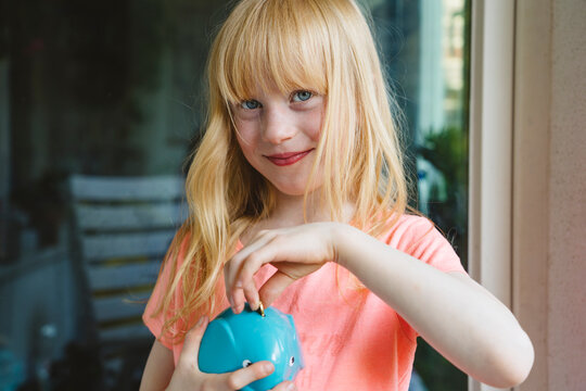 Smiling girl saving coin in piggy bank