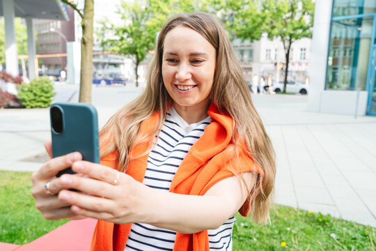 Smiling professional woman takes a selfie with her phone outdoors