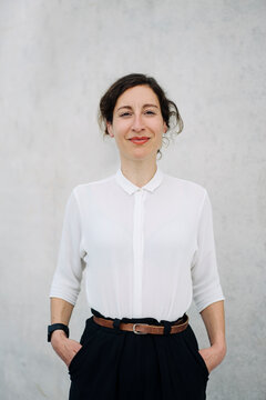 Portrait of a smiling businesswoman at a concrete wall