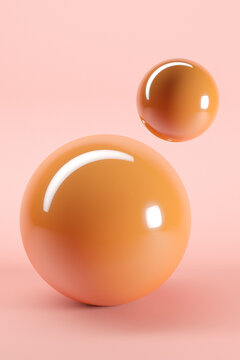 Three dimensional render of two orange glossy spheres against pink background