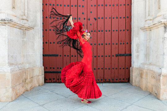 Female flamenco dancing with hands raised by door
