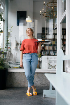 Young woman serving coffee and cake in a cafe