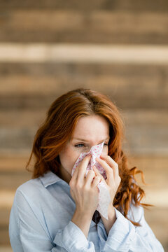 Redheaded woman blowing nose