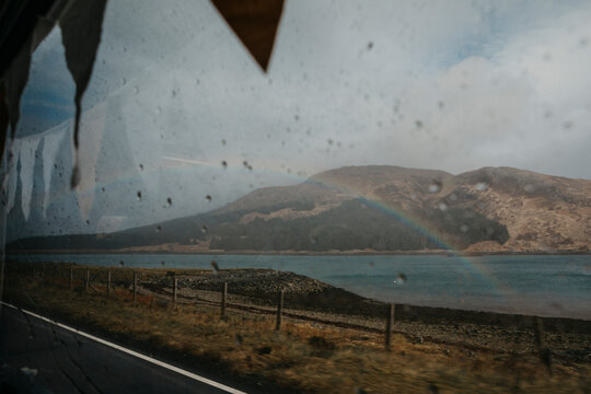 UK, Scotland, Highland, rainbow above the sea seen through car window