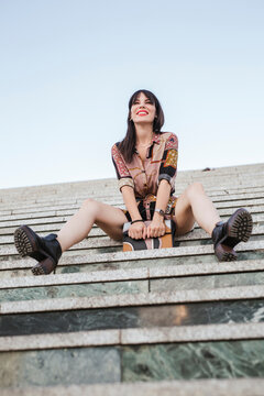 Young woman wearing patterned dress sitting on stairs