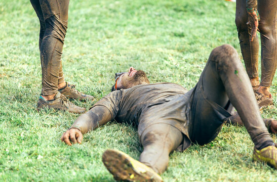 Participant in extreme obstacle race lying exhaustedly on grass