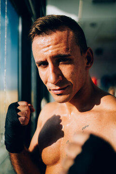 Portrait of confident boxer wearing bandages at the window