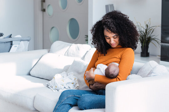 Mother breastfeeding and looking at son in living room