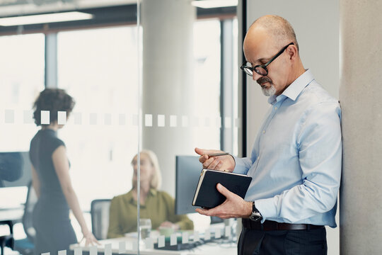 Businessman writing in book at modern London city office