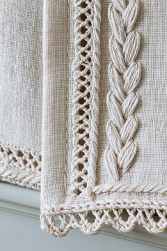 Closeup of hand-embroidered ivory linen towel edge with intricate cotton stitching and soft morning light illuminating the textile details