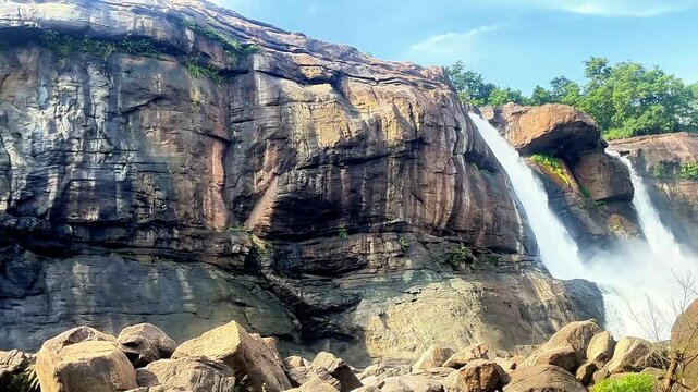 This waterfall flows through the lush Western Ghats, where the Chalakudy River cascades over broad rocky ledges into a misty forest gorge. Athirappilly Falls, Thrissur, Kerala, India.