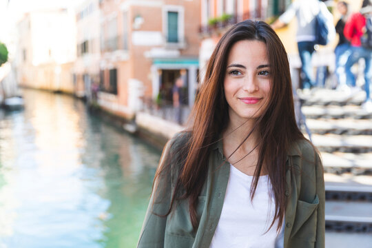 Italy, Venice, portrait of smiling young woman in the city with canal in background