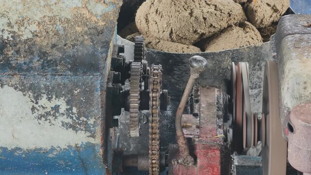 Close-up of gears, chain drive and pulleys operating a fish feed machine at floating fish farm