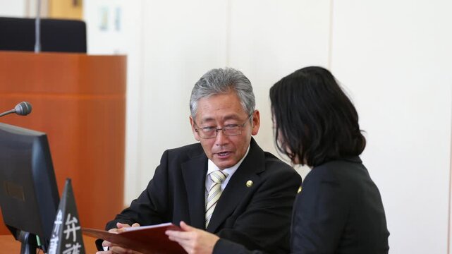法廷で打ち合わせを行う男女の弁護士