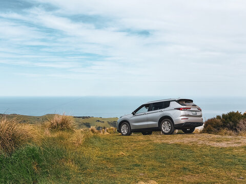 SUV parked on a coastal hilltop overlooking the ocean, Akaroa, New Zealand