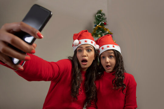 Mother and daughter making faces while clicking selfies together.  (Christmas) 