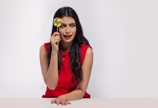 Portrait of a young woman holding a lollipop in hand.