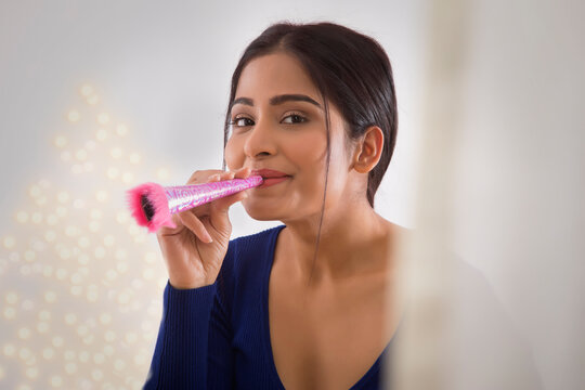Portrait of a young woman celebrating new years with a party blower in hand. 