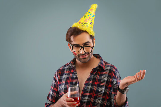 Young man wearing a party hat and holding a wine glass at new year eve party. 