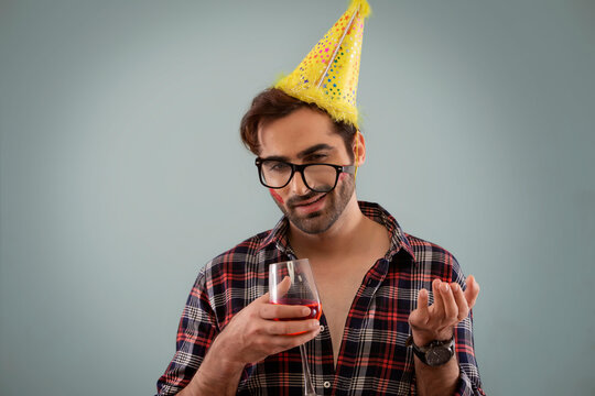 Young man wearing a party hat and holding a wine glass at new year eve party. 