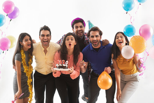 Group of friends celebrating new years together with balloons and cake. 
