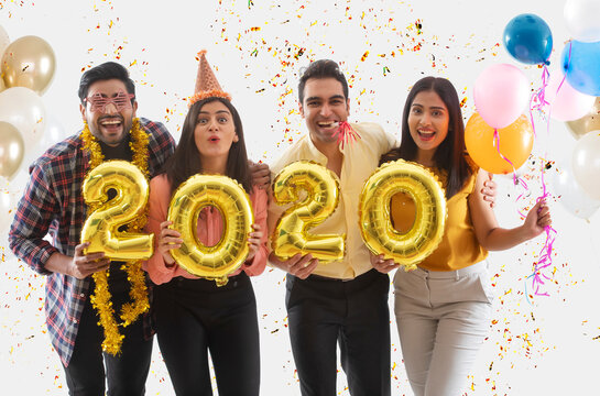 Friends celebrating new year holding 2020 balloons. 