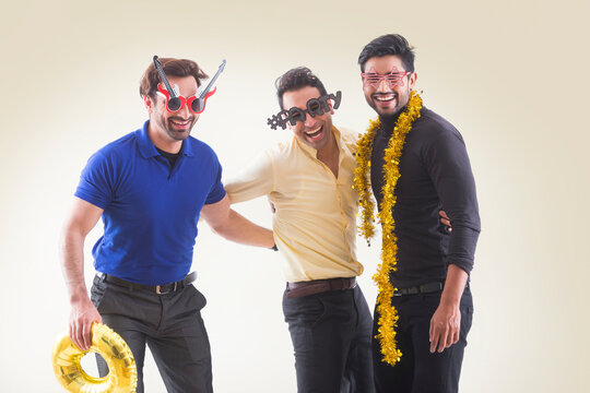 Young men in funky glasses having fun together at a party. 