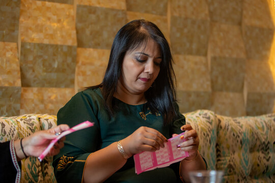 Woman taking her ticket to play Tambola with her friends. 