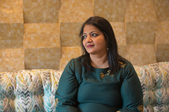 Portrait of a woman sitting on the couch lost in her thoughts. 