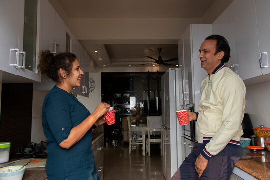 Husband and wife drinking coffee in the kitchen together at home. 