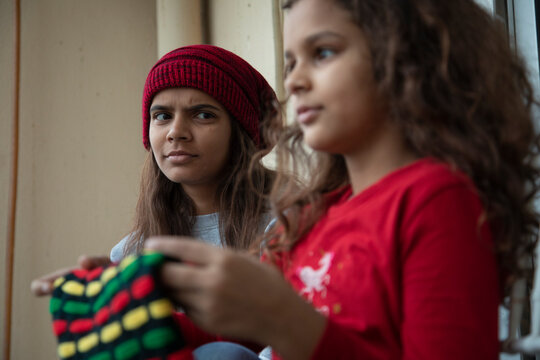 Girl sitting in the balcony looking suspiciously at her younger sister. (Children) 