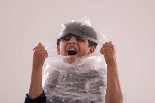 Young boy wrapped with plastic,struggling to tear for fresh air. (Children) 