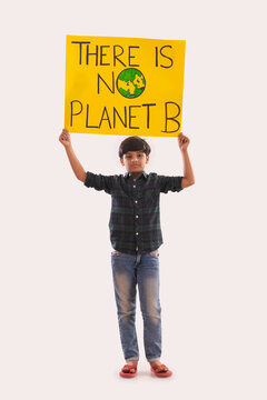 Young boy holding a placard in hand with a message to save mother earth. (Children) 