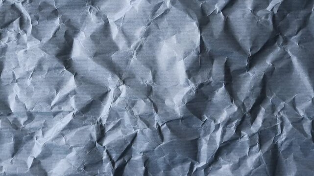 Static close-up video of wrinkled blue-gray wrapping paper with subtle horizontal stripes and pronounced fibers. A distressed grunge background for vintage, editorial and creative design projects.