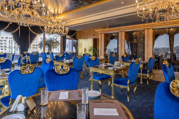 Naklejka premium Luxury restaurant dining hall with blue velvet chairs and chandeliers