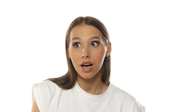 Portrait of a woman looking sideways with surprised expression, mouth open, makeup, on white background.