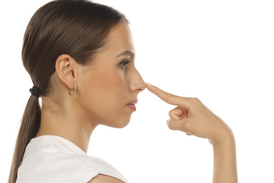 Side profile of a woman touching her nose, rhinoplasty concept, calm expression, on white background.