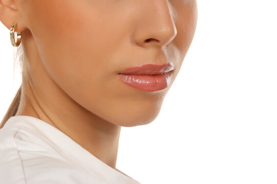 Beauty close-up of woman's lips, nose and chin profile, skin texture and gold earring, on white background