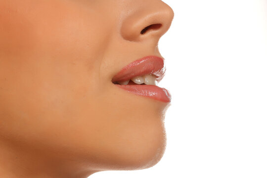 Extreme close-up of woman's mouth biting lip, teeth visible, glossy lipstick, profile view, on white background.