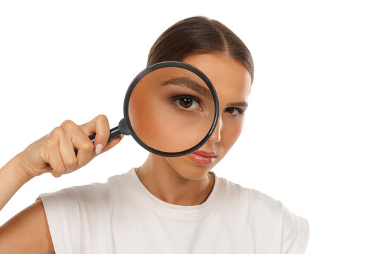 Portrait of woman holding magnifying glass over eye, detective search concept, on white background