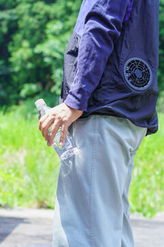 熱中症対策｜ファン付きウェアを着でペットボトルの水を持つ男性