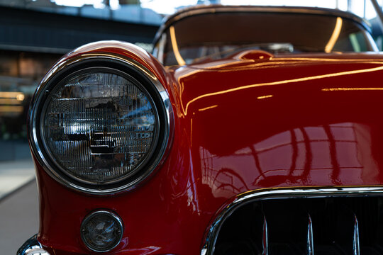 Front round headlight and chrome grille of classic red vintage car