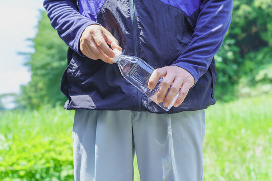 熱中症対策｜炎天下でペットボトルの水を持つ男性